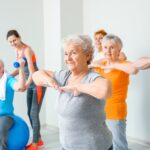 Seniorzy podczas zajęć ruchowych wykonują ćwiczenia poprawiające sprawność i kondycję