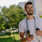 Mężczyzna podczas aktywności fizycznej trzyma butelkę z wodą i telefon